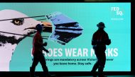 Essential workers walk past a 'Heroes Wear Masks' sign on the first day of a seven-day lockdown as the state of Victoria looks to curb the spread of a coronavirus disease (COVID-19) outbreak in Melbourne, Australia, May 28, 2021. REUTERS/Sandra Sanders/Fi