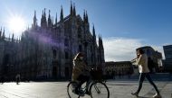 FILE PHOTO: People passes by the Duomo Cathedral, after Lombardy was downgraded from a red to an orange zone, loosening the coronavirus disease (COVID-19) restrictions including allowing non-essential shops to re-open, in Milan, Italy, April 13, 2021. REU