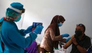 Man receives a dose of AstraZeneca coronavirus disease (COVID-19) vaccine as a healthcare worker wearing protective suits takes pictures of him in Jakarta, Indonesia, June 4, 2021. REUTERS/Willy Kurniawan