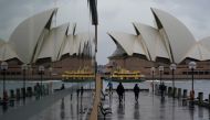 People walk in wet conditions along the waterfront near the Sydney Opera House as eastern Australia experiences a winter cold front, in Sydney, Australia, June 10, 2021. REUTERS/Loren Elliott