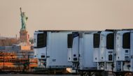 FILE PHOTO: Refrigerated tractor trailers used to store bodies of deceased people are seen at a temporary morgue, with the Statue of Liberty seen in the background, during the coronavirus disease (COVID-19) outbreak, in the Brooklyn borough of New York Ci