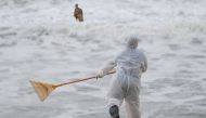 A Sri Lankan navy member throws a dead fish back to water while cleaning the debris washed to a beach from the MV X-Press Pearl container ship which caught fire and sank off the Colombo Harbour, in Ja-Ela, Sri Lanka June 14, 2021. REUTERS/Dinuka Liyanawat