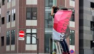 A worker attaches a Tokyo 2020 Olympic Games banner on a lamp post in Tokyo, Japan, June 16, 2021. (Reuters/Pawel Kopczynski)