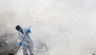 Sea water splashes behind a Sri Lankan navy member as he cleans the debris washed to a beach from the MV X-Press Pearl container ship, which caught fire and sank off the Colombo Harbour, in Ja-Ela, Sri Lanka June 14, 2021. REUTERS/Dinuka Liyanawatte
