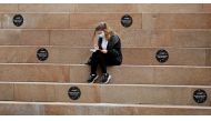 A woman wears a protective mask as she reads a book amongst social distancing markers, amid the outbreak of the coronavirus disease (COVID-19) in Liverpool, Britain, June 28, 2021. REUTERS/Phil Noble