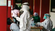 A healthcare worker in personal protective equipment takes a swab sample from a person to test for the coronavirus disease (COVID-19) during mass testing at a school in Jakarta, Indonesia, July 2, 2021. REUTERS/Ajeng Dinar Ulfiana
