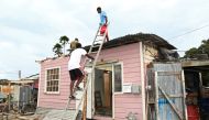 Men fix the roof of a house after strong winds of Hurricane Elsa passed St. Michael, Barbados July 2, 2021. (Reuters/Nigel Browne)