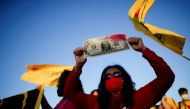 A demonstrator holds a replica of US dollar bill with the face of Brazil's President Jair Bolsonaro during a protest after entities and politicians called for impeachment against him, in front of the National Congress, in Brasilia, Brazil June 30, 2021. (