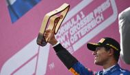 McLaren's Lando Norris celebrates after finishing third with the trophy on the podium Pool via REUTERS/Christian Bruna