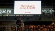 A man walks under a public health message about social distancing displayed at a shopping plaza in the city centre during a lockdown to curb the spread of a coronavirus disease (COVID-19) outbreak in Sydney, Australia, July 6, 2021. REUTERS/Loren Elliott/