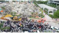 Members of the search and rescue team stand during a moment of silence and pray in front of the rubble of the collapsed Champlain Towers South building in Surfside, Florida, U.S. July 7, 2021, in this still image taken from drone footage obtained from soc