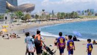 Children wear t-shirts of Barcelona soccer player Lionel Messi next to their parents at Barceloneta beach in Barcelona, Spain, July 14, 2021. REUTERS/Nacho Doce/File Photo