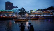 FILE PHOTO: People sit on the banks of the Singapore River at Clarke Quay in Singapore April 14, 2018. REUTERS/Thomas White/File Photo
