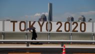 July 19, 2021 A woman shelters from the sun under an umbrella as she walks past Olympics signage REUTERS/Thomas Peter/File Photo