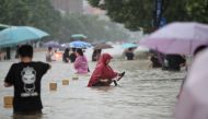 Residents wade through floodwaters on a flooded road amid heavy rainfall in Zhengzhou, Henan province, China July 20, 2021. (China Daily via REUTERS)