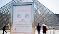 A sign asking for visitors' health passes is seen in front of the Louvre Pyramid amid the coronavirus disease (COVID-19) outbreak in Paris, France, July 21, 2021. (REUTERS/Sarah Meyssonnier)