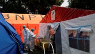 Healthcare workers in Personal Protective Equipment (PPE) work among temporary tents erected outside the emergency ward for accommodating the lack of beds at a government-run hospital amid the surge of coronavirus disease (COVID-19) in Bekasi, on the outs