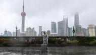 A man with luggage walks in the rain on The Bund as Typhoon In-fa approaches Shanghai, China July 25, 2021. cnsphoto via REUTERS