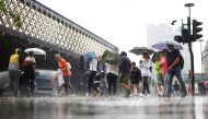 People walk through heavy rainfall, amid the coronavirus disease (COVID-19) outbreak, in London, Britain, July 25, 2021. REUTERS/Henry Nicholls
