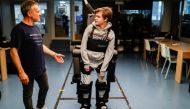 :Jean-Louis Constanza, Chief Business and Clinical Officer at French company Wandercraft helps his 16-year-old son Oscar using a robot exoskeleton at the company headquarters in Paris, France July 9, 2021. Picture taken July 9, 2021. REUTERS/Christian Har