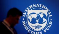A man stands near a logo of International Monetary Fund. (Reuters/File Photo)