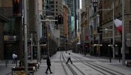 People in protective face masks walk through the quiet city centre during a lockdown to curb the spread of a coronavirus disease (COVID-19) outbreak in Sydney, Australia, July 28, 2021. REUTERS/Loren Elliott
