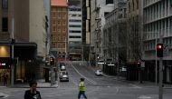 People with protective face masks walk through the quiet city centre during a lockdown to curb the spread of a coronavirus disease (COVID-19) outbreak in Sydney, Australia, July 28, 2021. REUTERS/Loren Elliott