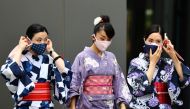 Women in traditional costumes, wearing protective face masks, walk outside the National Stadium, the main venue of the Tokyo 2020 Olympic Games, amid the coronavirus disease (COVID-19) outbreak, in Tokyo, Japan, August 3, 2021. Reuters/Kim Kyung-Hoon