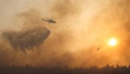 A firefighting helicopter makes a water drop as a wildfire continues to rage at Varympompi suburb north of Athens, Greece, August 4, 2021. REUTERS/Giorgos Moutafis
