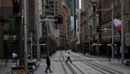 People in protective face masks walk through the quiet city centre during a lockdown to curb the spread of a coronavirus disease (COVID-19) outbreak in Sydney, Australia, July 28, 2021. REUTERS/Loren Elliott
