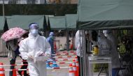 A medical worker collects a swab from a person at a nucleic acid testing site at a park, following new cases of the coronavirus disease (COVID-19), in Beijing, China August 6, 2021. REUTERS/Tingshu Wang
