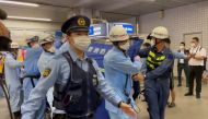 Police escort rescue workers carrying a person through a train station after a knife attack on a train in Tokyo, Japan August 6, 2021 in this still image taken from video obtained by Reuters