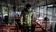 A policeman inspects an ID of a bus passenger passing through a checkpoint on the first day of a two-week lockdown to prevent the spread of the highly infectious coronavirus Delta variant, in Quezon City, Metro Manila, Philippines, August 6, 2021. Reuters