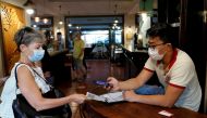 A woman has her Green Pass (health pass) checked before entering a pizzeria as Italy brings in tougher restrictions where a proof of immunity will be required to access an array of services and leisure activities, in Rome, Italy, August 6, 2021. REUTERS/R