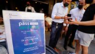 A man shows his COVID-19 health pass at a restaurant as France brings on tougher restrictions where a proof of immunity will now be required to access most public spaces and to travel by inter-city train, in Nice, France, August 9, 2021. REUTERS/Eric Gail