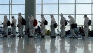 Passengers wearing protective suits (PPE) line up to board their plane for an international flight at Hong Kong airport amid the spread of the coronavirus disease (COVID-19), China July 9, 2021. REUTERS/Thomas Peter/File Photo