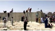 People climb a barbed wire wall to enter the airport in Kabul, Afghanistan August 16, 2021, in this still image taken from a video. Reuters TV/via Reuters/File Photo