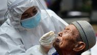 A healthcare worker wearing personal protective equipment suits (PPE) takes a swab sample from an elderly man with mental illness to test for the coronavirus disease (COVID-19) at a social home in Jakarta, Indonesia, August 23, 2021. REUTERS/Ajeng Dinar U