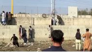 People stand on a barrier outside Kabul airport, Afghanistan, August 22, 2021 in this still image taken from video. REUTERS/ReutersTV