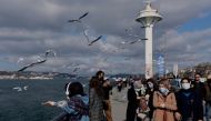 People wearing protective masks stroll by the Bosphorus, amid the coronavirus disease (COVID-19) outbreak in Istanbul, Turkey February 25, 2021. REUTERS/Murad Sezer
