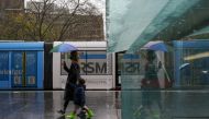 A masked woman with an umbrella walks with a child through the quiet city centre during a lockdown to curb the spread of a coronavirus disease (COVID-19) outbreak in Sydney, Australia, August 24, 2021. REUTERS/Loren Elliott