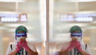 A person wearing a face shield and protective face masks uses her phone at the shopping mall on the first day of coronavirus restrictions lift on retail and dining in Bangkok and other high-risk areas to revive the economy, as the country battles its wors