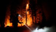 Patrick R., 27, a firefighter with Cal Fire sprays water on hot spots as flames from the Caldor Fire burn through trees in Christmas Valley near South Lake Tahoe, California, U.S., August 31, 2021. REUTERS/Brittany Hosea-Small