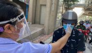 A health worker checks the temperture of a motorcycle driver at a check point during the first day of the extended lockdown in Hanoi, Vietnam, September 6, 2021. REUTERS/Stringer
