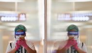 A person wearing a face shield and protective face masks uses her phone at the shopping mall on the first day of coronavirus restrictions lift on retail and dining in Bangkok and other high-risk areas to revive the economy, as the country battles its wors
