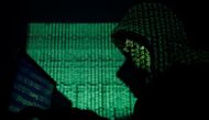 A hooded man holds a laptop computer as cyber code is projected on him in this illustration picture taken on May 13, 2017. REUTERS/Kacper Pempel/Illustration