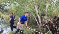 Sgt. Devin Coulon and Cpl. Chance Woods of the St. Tammany Parish Sheriff's Office searching for an Alligator believed to have killed a man after Hurricane Ida in Slidell, Louisiana, in this handout picture obtained by Reuters on September 14, 2021. St. T