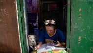 Annie Sabino, 16, a grade 9 student, completes her school work next to her dog, while tending to her family's sidewalk eatery beside their home, as schools remain closed during the coronavirus disease (COVID-19) outbreak, in Manila, Philippines, January 6