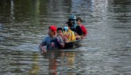 People sit on a makeshift boat as a man pulls it through a flooded street in Chaiyaphum province, Thailand, September 28, 2021. REUTERS/Panumas Sanguanwong