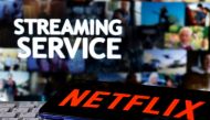 A smartphone with the Netflix logo is seen on a keyboard in front of displayed 